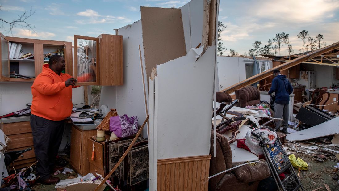 Granadas Baker and his son Granadas Jr. retrieve personal items from their damaged home in Beauregard.