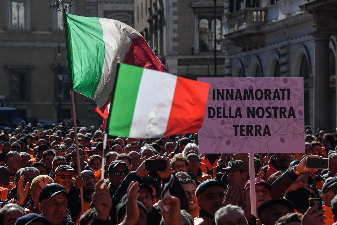 Olive oil farmers from Puglia, one carrying a sign reading "In love with our land," protest during this year's olive oil crisis in February.