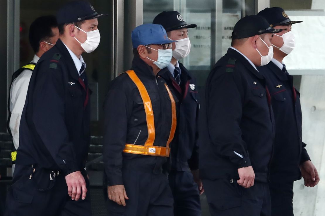 Carlos Ghosn, wearing a light blue cap, left a Tokyo detention center on Wednesday after more than 100 days in detention.