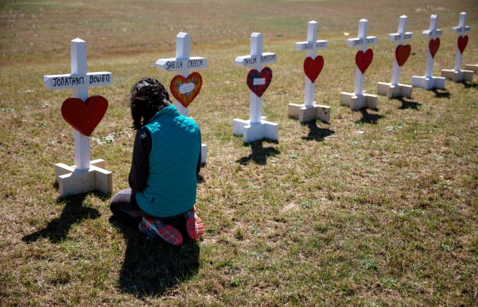 Jessica Taylor prays in front of a cross for Jonathan Bowen, 9, at a makeshift memorial for the victims in Beauregard. "I have a son his age," Taylor said. "I can't imagine that mother's loss."