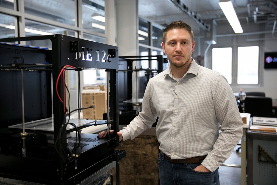 Zac DiVencenzo, COO of Juggerbot 3D, stands next to a 3D printer.