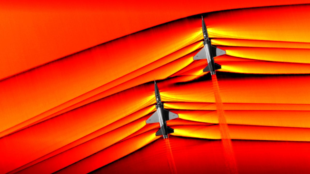 Using the schlieren photography technique, NASA was able to capture the first air-to-air images of the interaction of shockwaves from two supersonic aircraft flying in formation. These two U.S. Air Force Test Pilot School T-38 aircraft are flying in formation, approximately 30 feet apart, at supersonic speeds, or faster than the speed of sound, producing shockwaves that are typically heard on the ground as a sonic boom. The images, originally monochromatic and shown here as colorized composite images, were captured during a supersonic flight series flown, in part, to better understand how shocks interact with aircraft plumes, as well as with each other. Credits: NASA Photo
