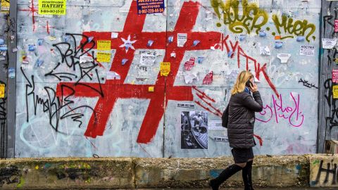 A woman walks past a graffiti covered wall with a giant hashtag sign near Moscow's Kursky railway station on November 17, 2017.