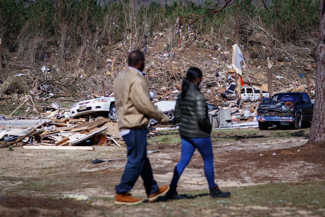 Krystal Stenson-Garrett walks with her husband, Shaun, through the wreckage where her family's homes used to be.