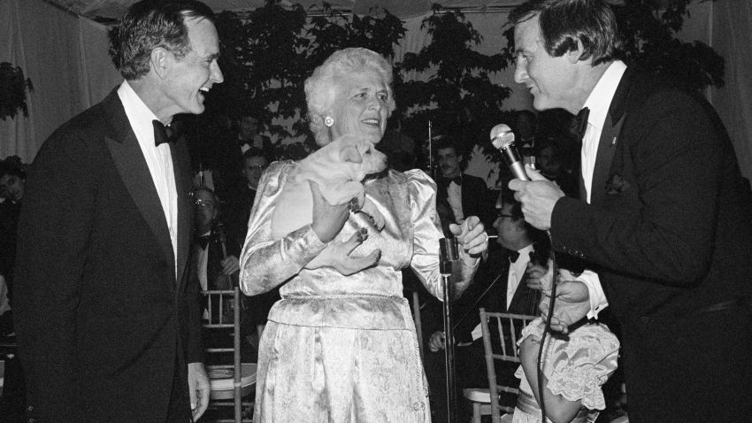 Vice President George H.W. Bush and his wife Barbara react to the gift of a puppy from film producer Jerry Weintraub, right, Saturday evening, May 14, 1983, in Malibu, Calif. The Bushes were guests of honor at a formal dinner hosted by Weintraub and attended by many prominent Southern Californians. (AP Photo/Reed Saxon)