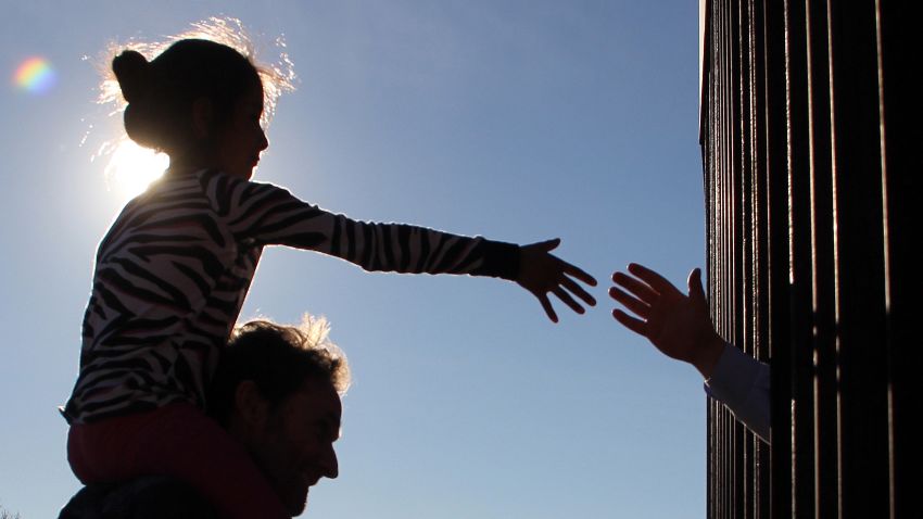 A girl from Anapra, a neighbourhood on the outskirts of Ciudad Juarez in Mexico, touches hands with a person on the United States through the border fence, during a prayer with priests and bishops from both countries to ask for the migrants and people of the area, on February 26, 2019. - Built two years ago, the Anapra fence is one of several reinforced border barriers that the administration of US President Donald Trump calls the first sections of the wall. (Photo by Herika MARTINEZ / AFP) (Photo credit should read HERIKA MARTINEZ/AFP/Getty Images)
