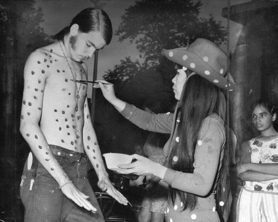 Kusama applies dots of paint to a subject's torso. She often used human bodies as canvases.