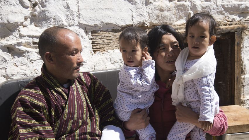 Mother (2R) of twins Nima (R) and Dawa Pelden (2L), holds them as her husband Sonam Tshering (L), looks on at Tachogang Lhakhang Monastery, in Paro Valley on March 7, 2019. - Bhutan's first conjoined twins Nima and Dawa Pelden made a triumphant return to their home country on March 7 able for the first time in their lives to move around without falling over each other. (Photo by STR / AFP)        (Photo credit should read STR/AFP/Getty Images)