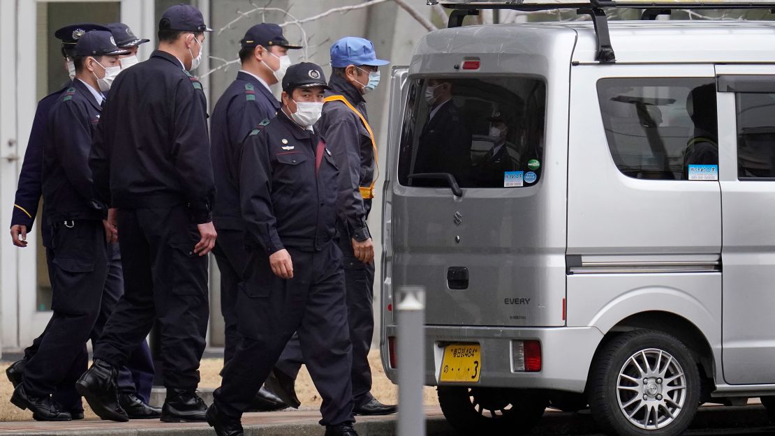 Carlos Ghosn walks into a van with a ladder on its roof.