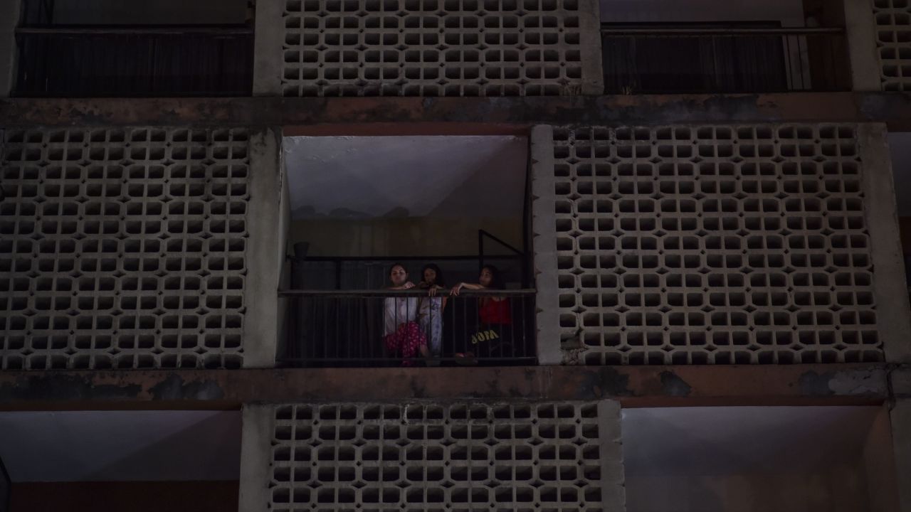 Women look out from an apartment building during a power outage Thursday in Caracas.