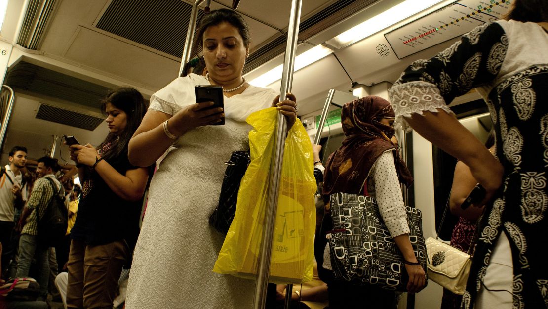 Indian women use their smartphones as they travel in the carriage reserved for women on the metro in New Delhi on July 3, 2015.  