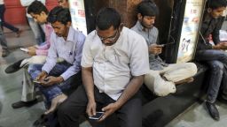 Passengers using smartphones at the central railway station in Mumbai.