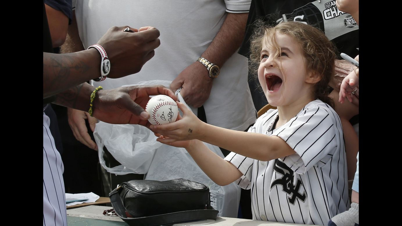 Six-year-old Joan Stiltner receives an autographed baseball from Chicago White Sox left fielder Joel Booker before the team's spring training game against the Milwaukee Brewers on Thursday, March 7, in Glendale, Arizona.