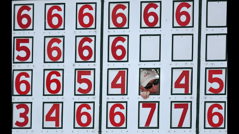 A scoreboard worker watches golf through a hole in the board during the second round of the Arnold Palmer Invitational at the Bay Hill Club on March 8, in Orlando, Florida.