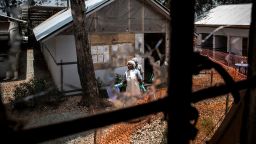 TOPSHOT - Health workers are seen through a bullet hole left in the window of an Ebola treatment centre, which was attacked in the early hours of the morning on March 9, 2019 in Butembo. - Armed men on March 9 attacked an Ebola treatment centre in the east of the Democratic Republic of Congo, killing a policeman and wounding a health worker, the authorities said. Suspected Mai-Mai rebels have attacked the Butembo ETC twice in the last two weeks. (Photo by JOHN WESSELS / AFP)        (Photo credit should read JOHN WESSELS/AFP/Getty Images)