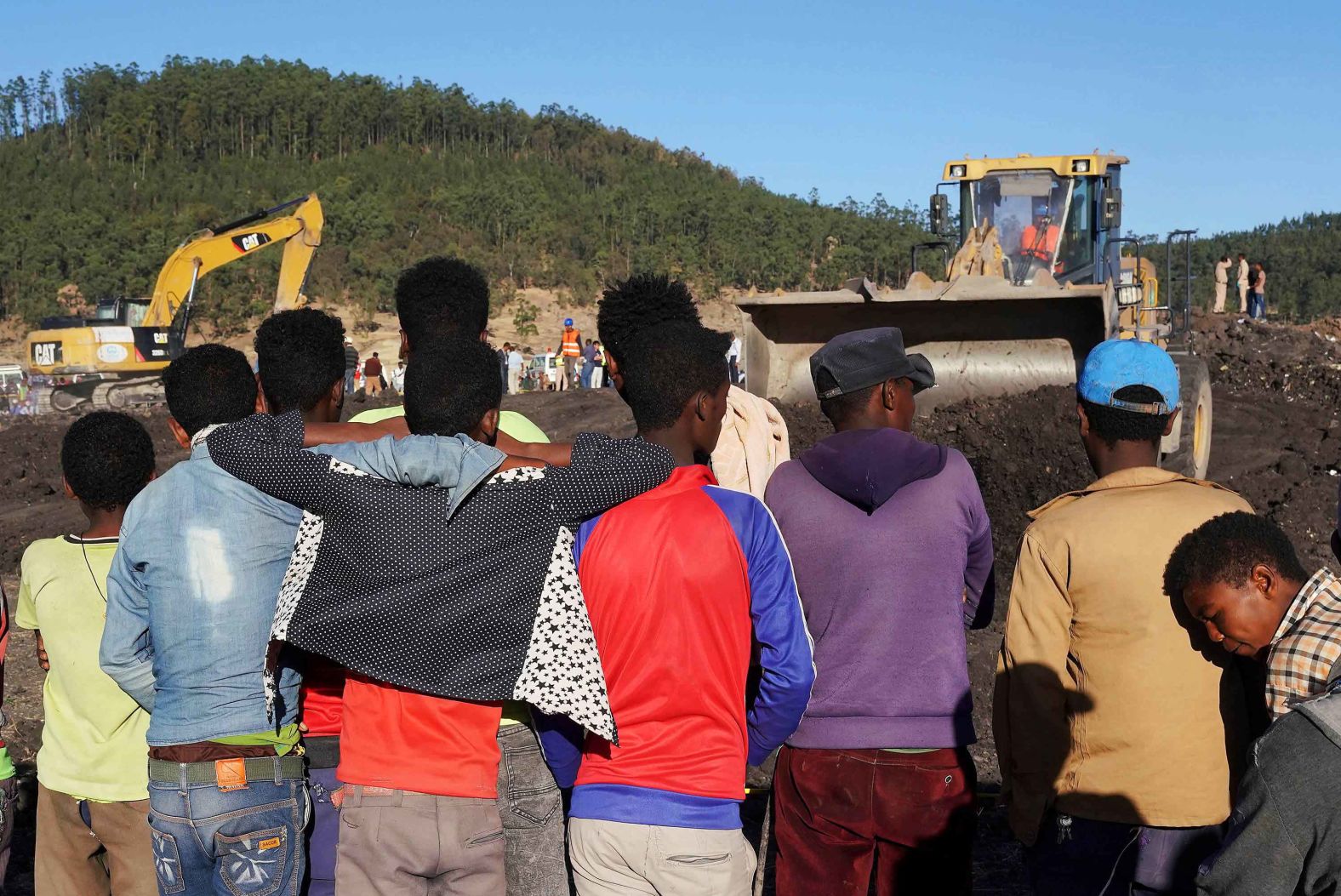 People watch workers at the wheat field where the plane crashed.