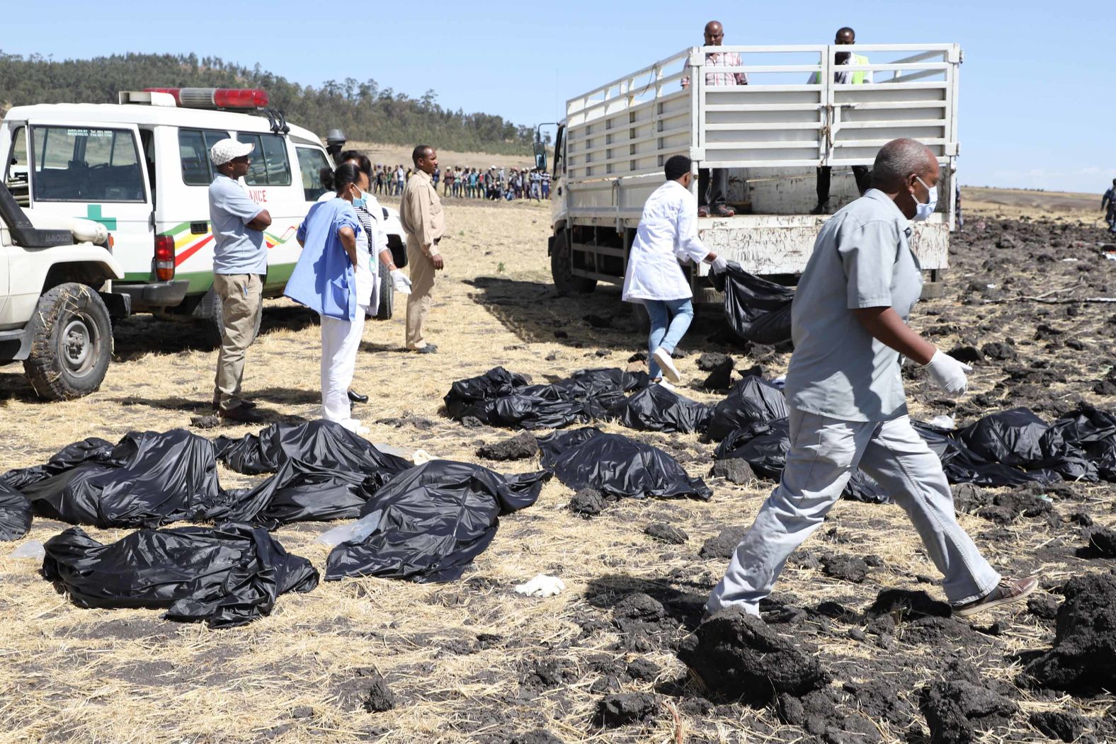 Emergency workers move around body bags on Sunday, March 10.