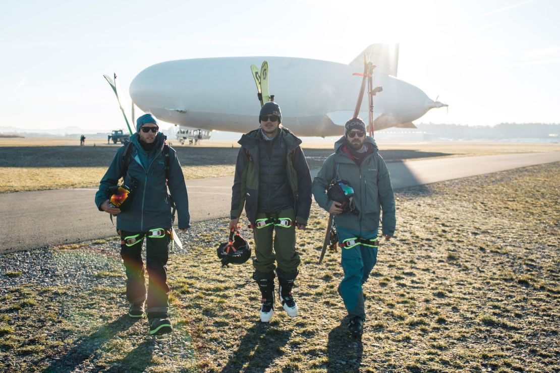 The freeriding trio pose in front of the airship.