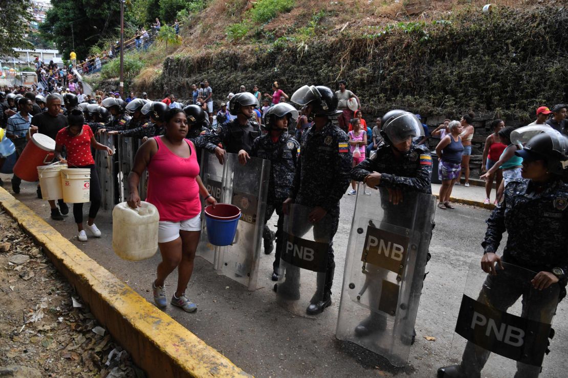 Police help distribute drinking water in Caracas on March 11.