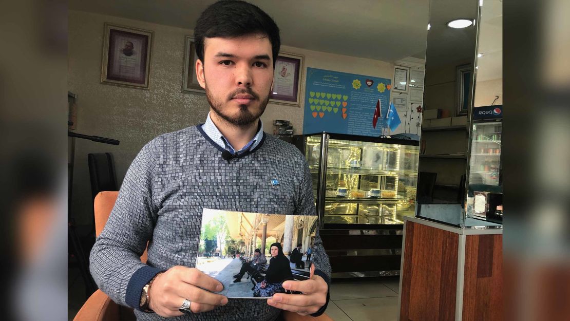 Ishqiyar Abudureyimu holds up a picture of his mother outside Istanbul's Hagia Sophia mosque. He says this is the last time he saw her and that she has disappeared since she returned to China.