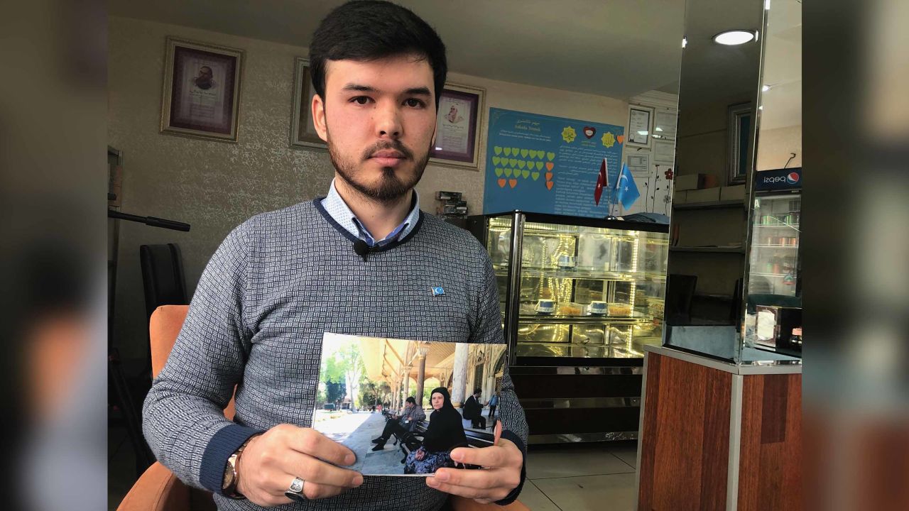 Ishqiyar Abudureyimu holds up a picture of his mother outside Istanbul's Hagia Sophia mosque. He says this is the last time he saw her and that she has disappeared since she returned to China.