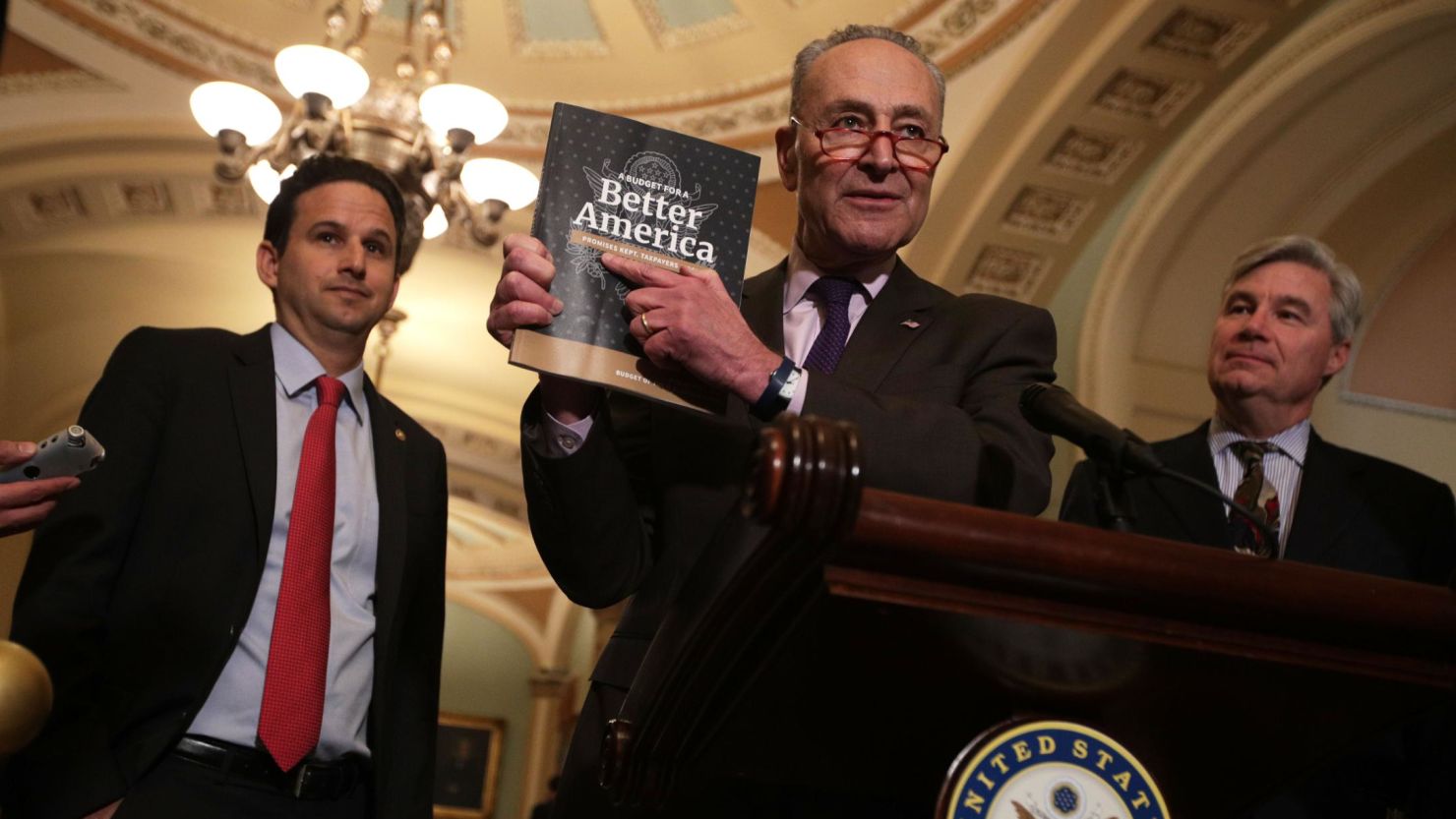 U.S. Senate Minority Leader Sen. Chuck Schumer (D-NY) (2nd L) holds up a copy of U.S. President Donald Trump's FY2020 budget request as Sen. Brian Schatz (D-HI) (L) and Sen. Sheldon Whitehouse (D-RI) (R) look on during a news briefing after the weekly Senate Democratic policy luncheon March 12, 2019 at the U.S. Capitol in Washington, DC.   (Alex Wong/Getty Images)