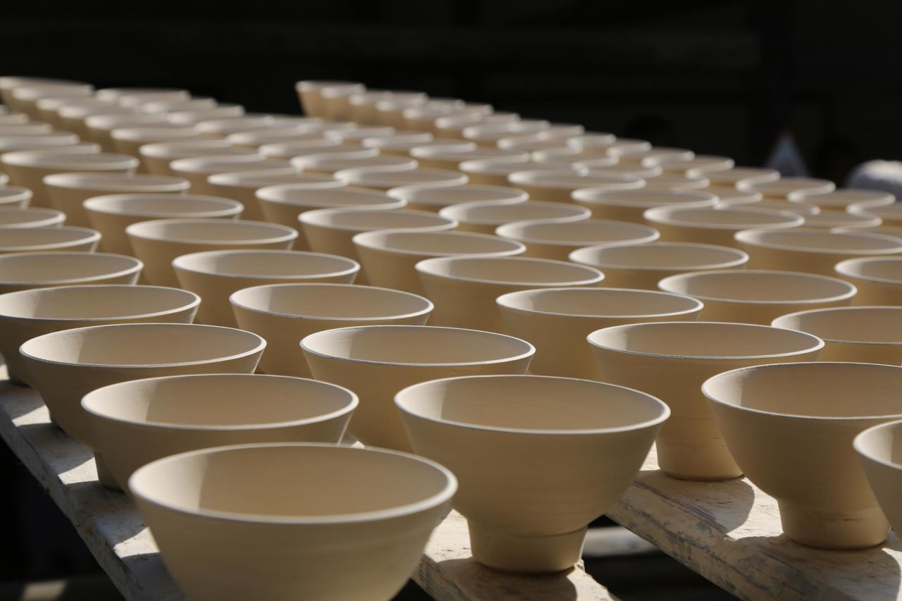 Unfired bowls are carefully placed on narrow strips of wood. Within old 72 specialties in Jingdezhen's ceramic industry, some potters go back and forth carrying strips of unfired bowls with delicate balance. 