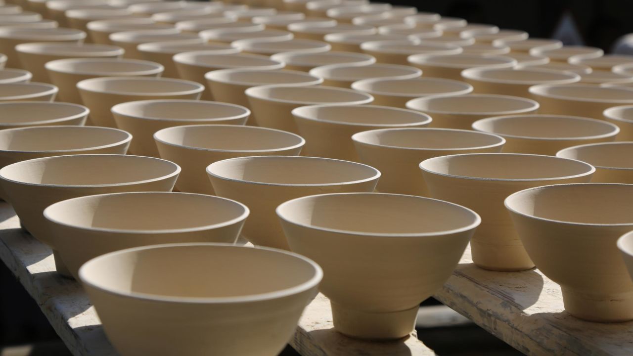 Unfired bowls are carefully placed on narrow strips of wood. Within old 72 specialties in Jingdezhen's ceramic industry, some potters go back and forth carrying strips of unfired bowls with delicate balance. 