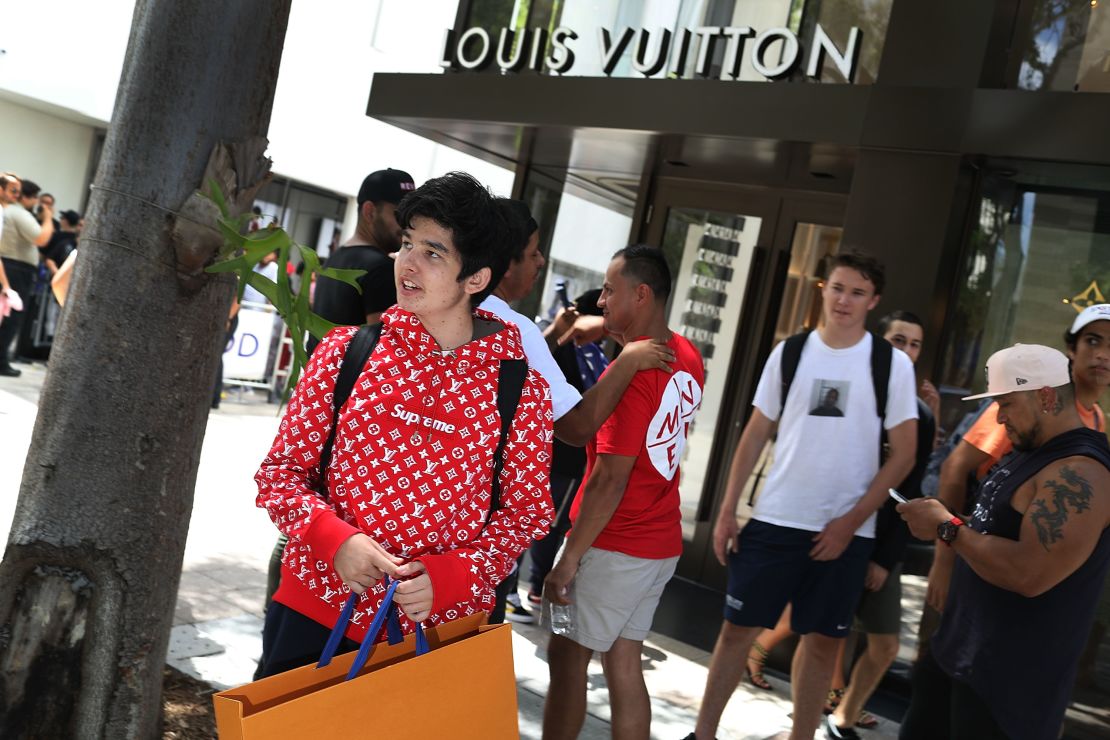 A shopper wears a Supreme/Louis Vuitton hoodie outside a  Louis Vuitton store in Miami.