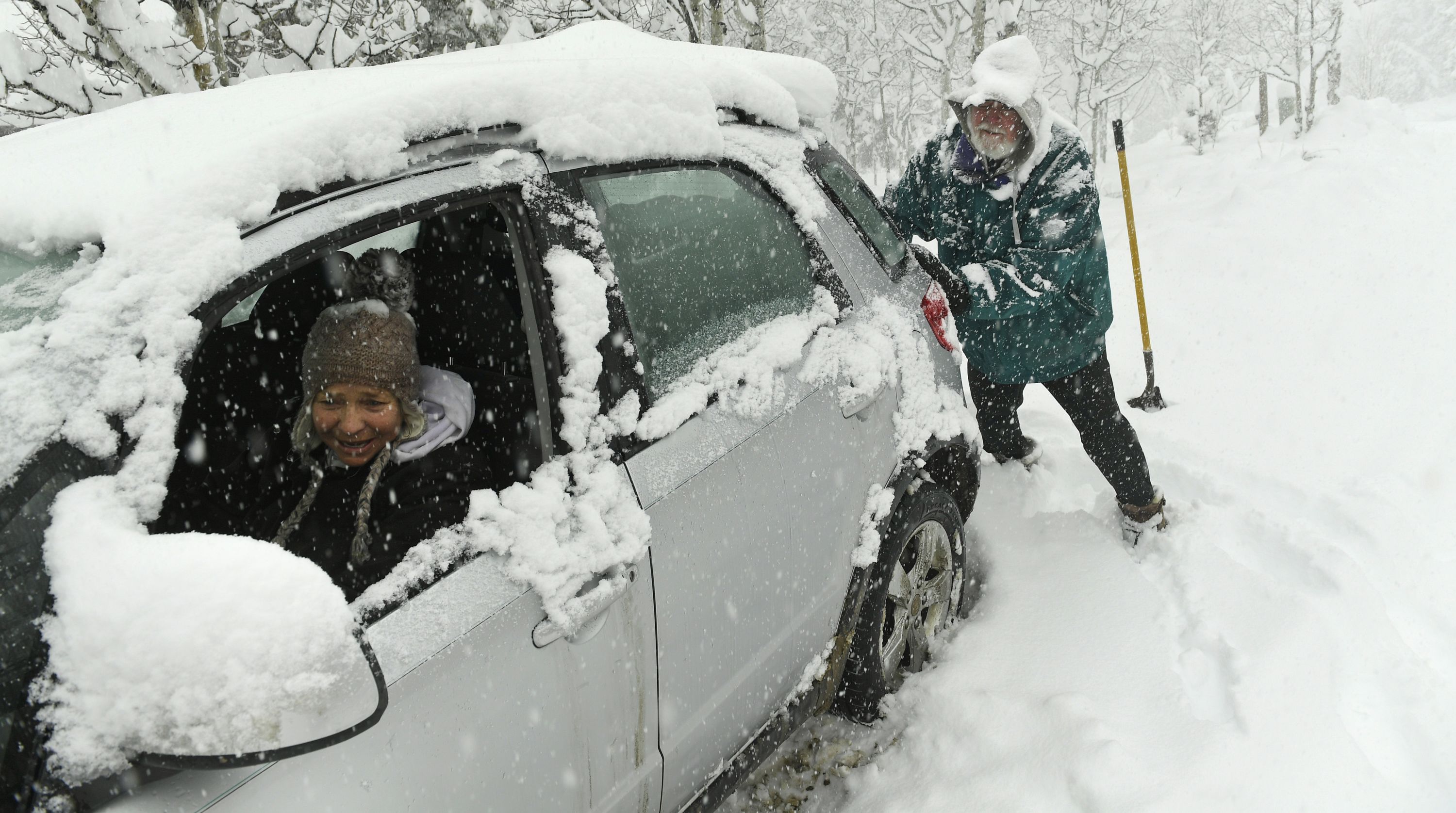 Linda Hurth, in the driver's seat, tells her husband, Ed McCaffrey, when to push as they try to get her car unstuck from the snow on Wednesday, March 13, in Nederland, Colorado. Blizzard  warnings were issued across the state.