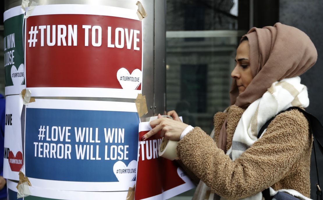 A demonstrator hangs banners from multi-faith group 'Turn to Love' during a vigil at New Zealand House in London.
