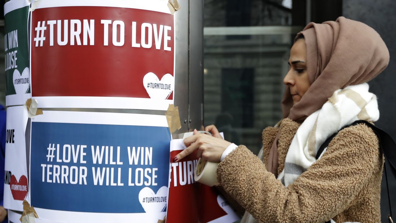 A demonstrator hangs banners from multi-faith group 'Turn to Love' during a vigil at New Zealand House in London.