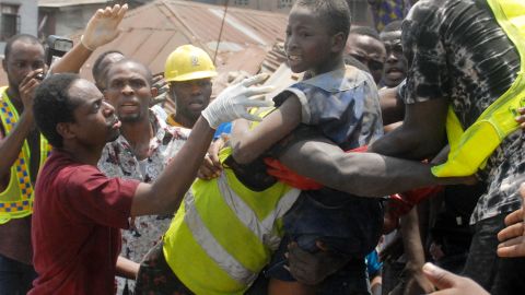 Emergency personnel rescue a child at the site of a building which collapsed in Lagos on March 13, 2019. 