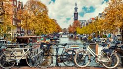 Bike over canal Amsterdam city. Picturesque town landscape in Netherlands with view on river Amstel. 