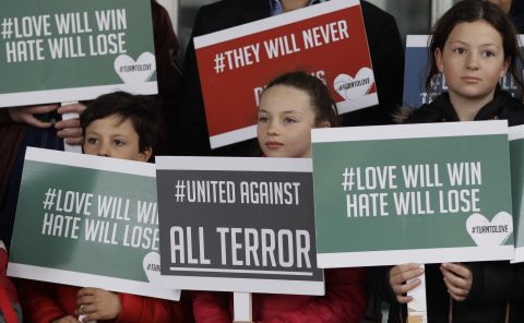 Young demonstrators hold banners from the multifaith group Turn to Love during a vigil at the New Zealand House in London.
