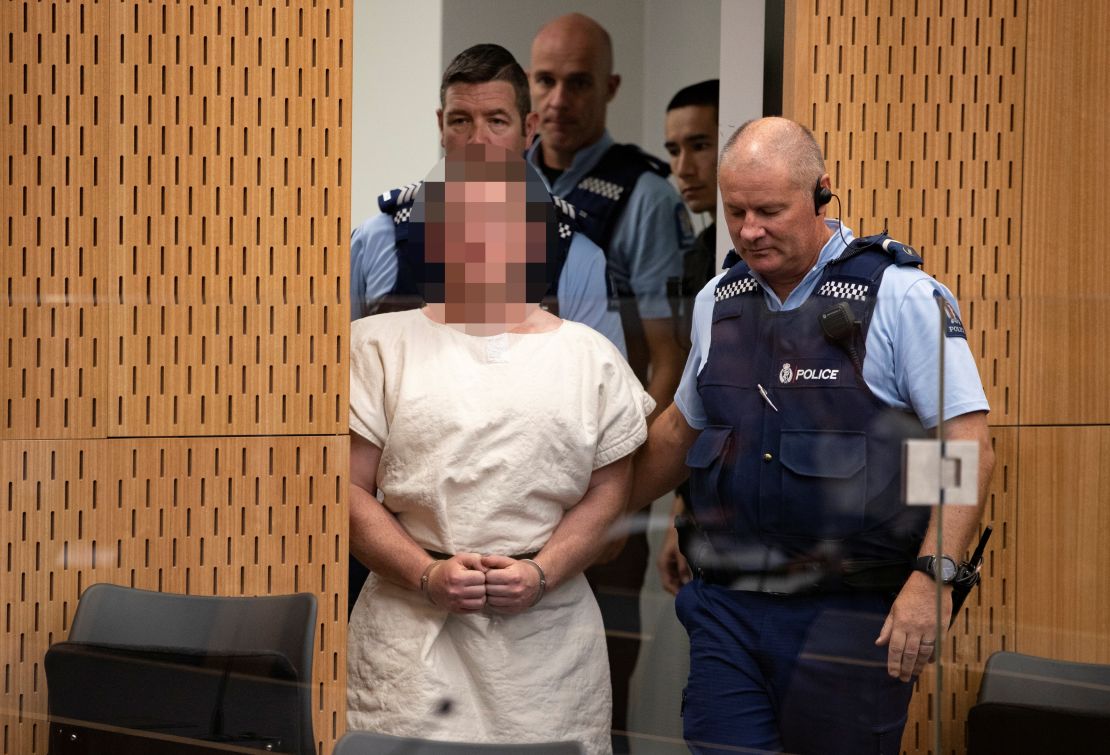 Tarrant is escorted into Christchurch District Court on Saturday. The judge ruled pictures of the suspect in court must have his face blurred.