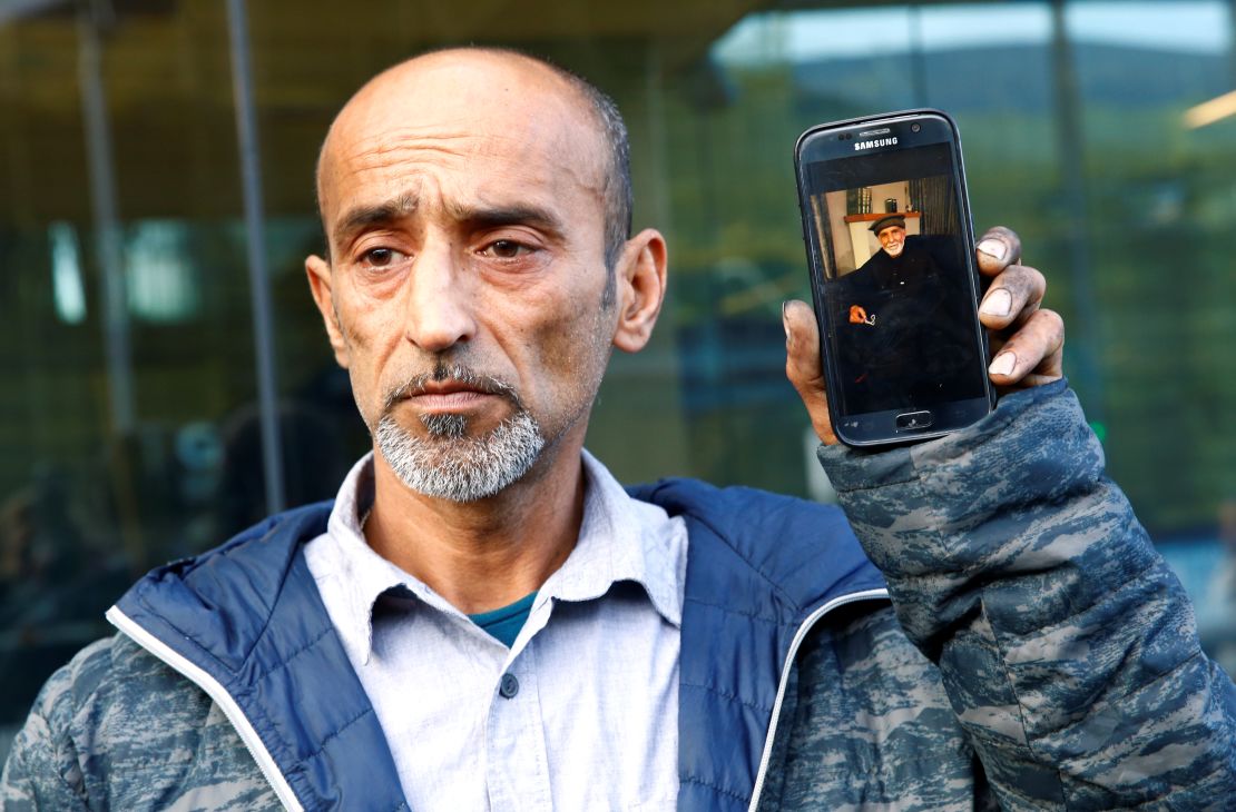 Omar Nabi holds up a phone displaying a photo of his dead father Haji Daoud, at the district court in Christchurch.