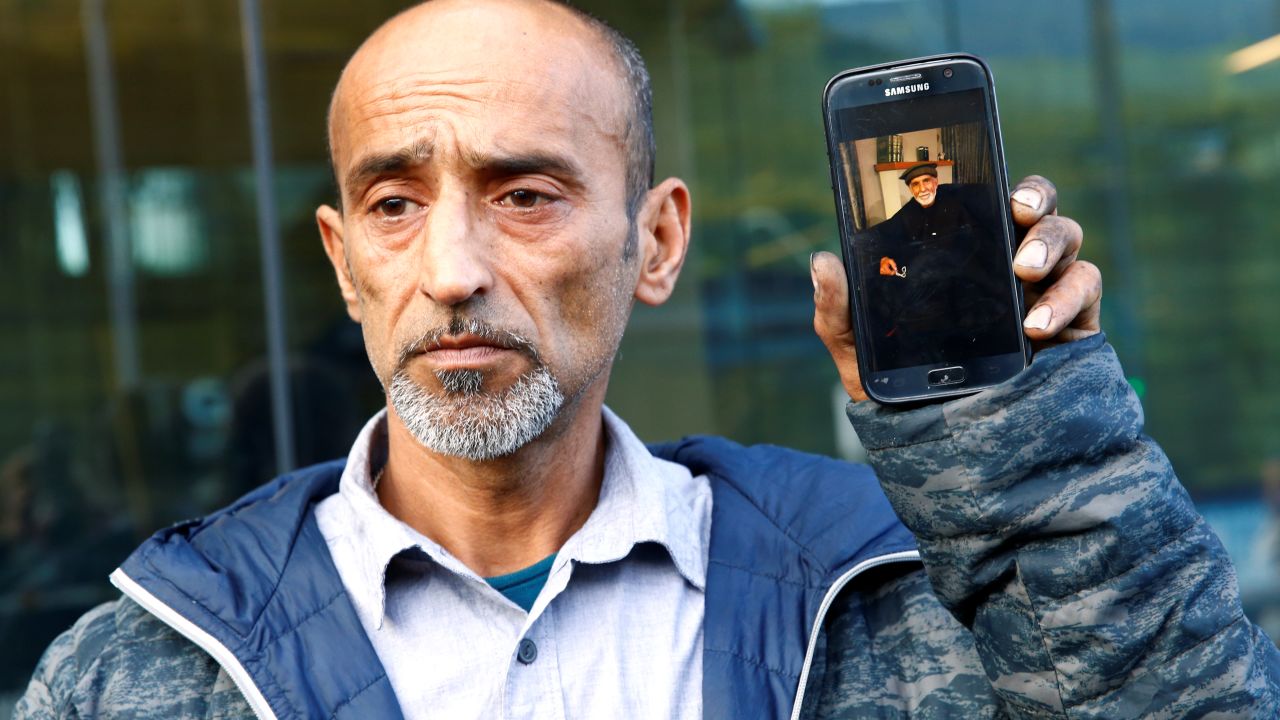 Omar Nabi holds up a phone displaying a photo of his dead father Haji Daoud, at the district court in Christchurch.
