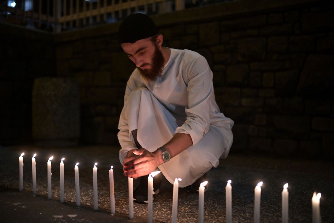 A well-wisher helps light dozens of candles as he pays respects to victims outside the hospital in Christchurch Saturday.