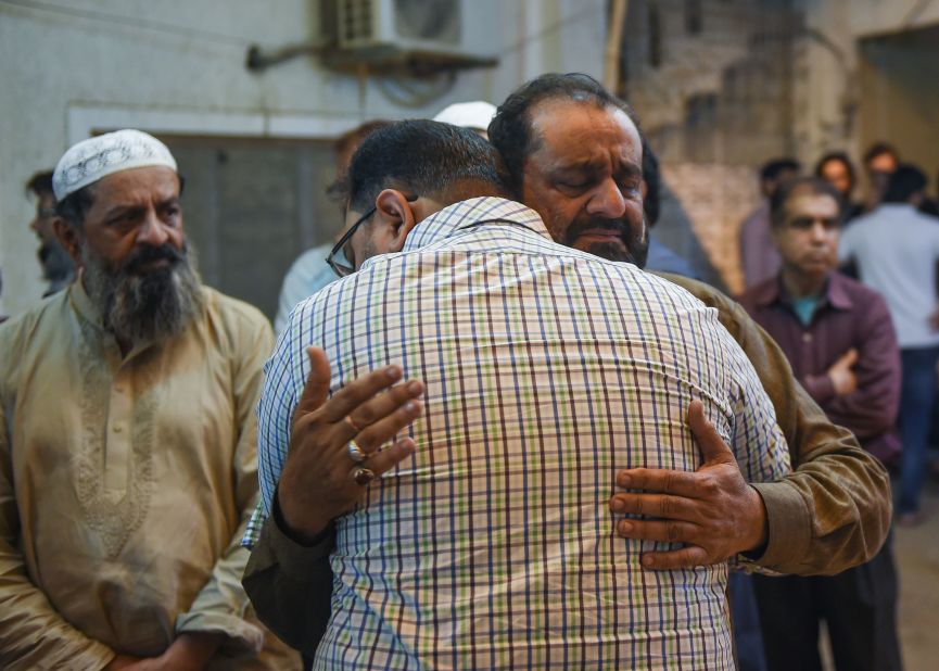A Pakistani man embraces the father of Syed Areeb Ahmed (right), reportedly gunned down in the New Zealand massacre, in Karachi on March 16.
