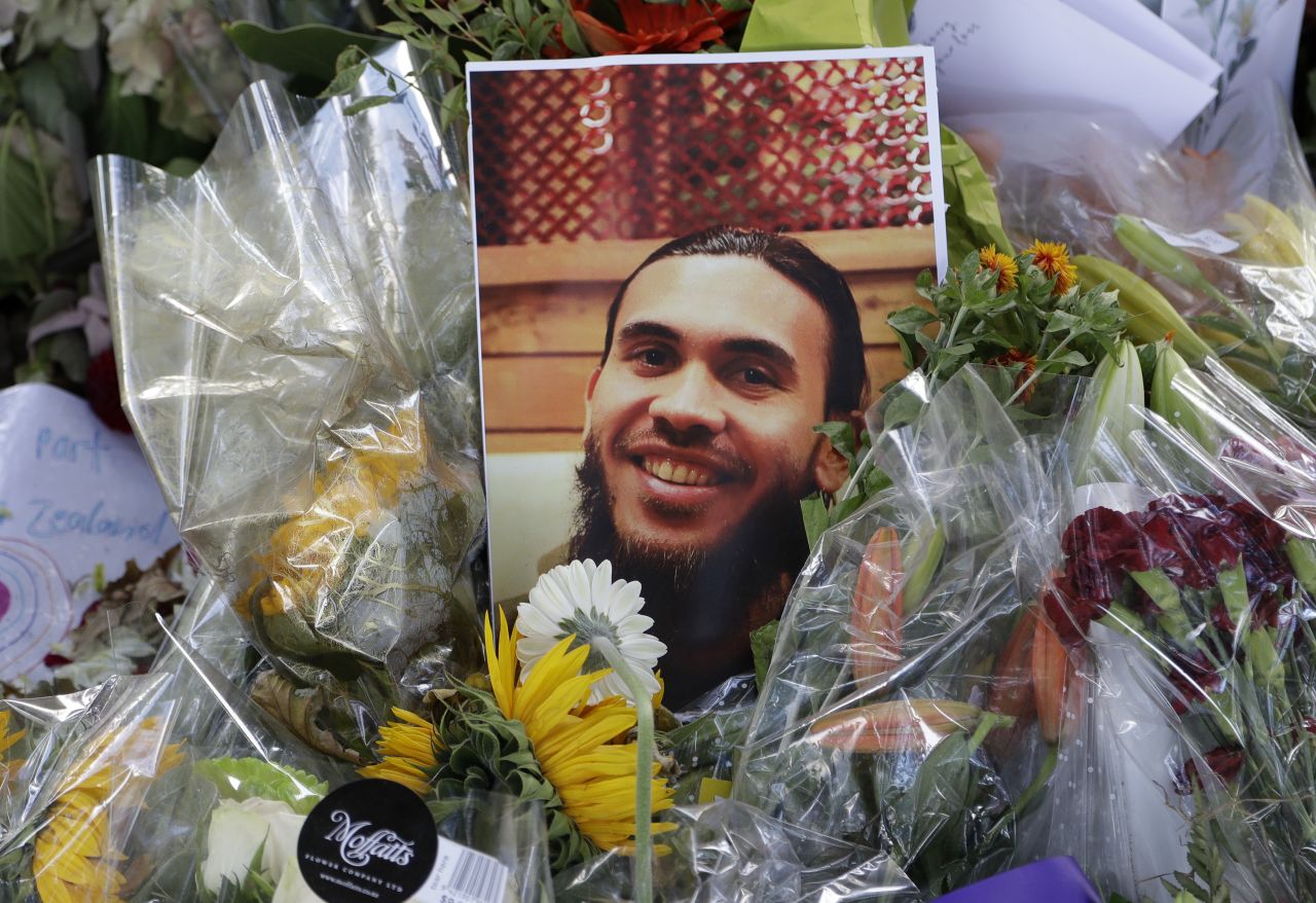 A photo tribute for Christchurch mosque shooting victim Tariq Omar lies amid mounds of flowers across the road from the Al Noor mosque in Christchurch, New Zealand Tuesday, March 19.
