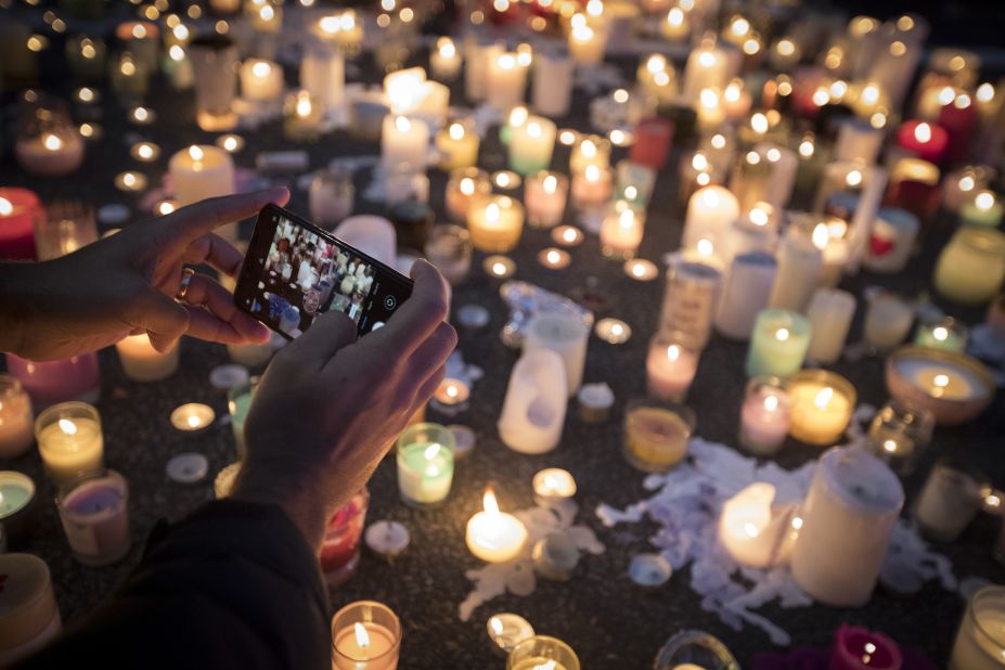A mourner takes a picture of candles commemorating victims of Friday's shooting, outside the Al Noor mosque in Christchurch, New Zealand, Monday, March 18. Three days after the attack, New Zealand's deadliest shooting in modern history, relatives were anxiously waiting for word on when they can bury their loved ones.