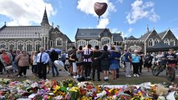 TOPSHOT - A group of students (C) sings in front of flowers left in tribute to victims at the Botanical Garden in Christchurch on March 19, 2019, four days after a shooting incident at two mosques that claimed the lives of 50 people. - New Zealanders have begun handing in weapons in response to government appeals following the Christchurch massacre, but the gesture has put some squarely in the social media firing line. (Photo by Anthony WALLACE / AFP)        (Photo credit should read ANTHONY WALLACE/AFP/Getty Images)