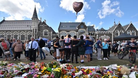 A group of students sings in front of a floral tribute to victims of the mosque shootings in Christchurch.