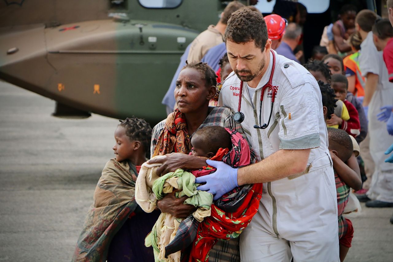 Survivors are escorted to safety by aid workers at the airport in Beira on March 19.