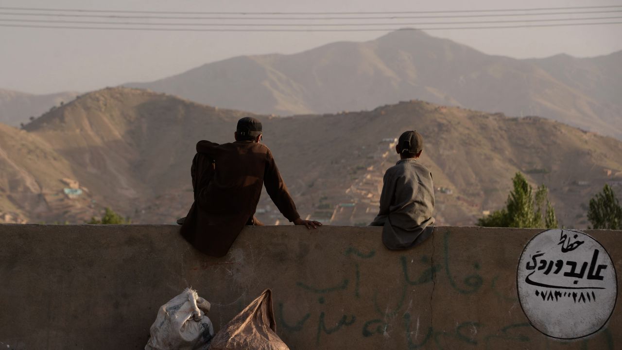 A pair of young Afghans sit on a wall as they watch a game on the outskirts of Kabul. "When I started filming them, they didn't have a grass pitch in the whole country. A lot of the guys had never played with a leather ball," Albone reflects.