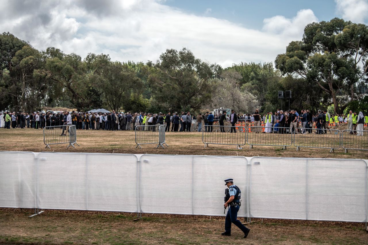 An armed policeman walks alongside a fence at Memorial Park Cemetery as a funeral takes place for two of the victims of the Christchurch attack on March 20 in Christchurch.