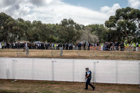 An armed policeman walks alongside a fence at Memorial Park Cemetery as a funeral takes place for two of the victims of the Christchurch attack on March 20 in Christchurch.