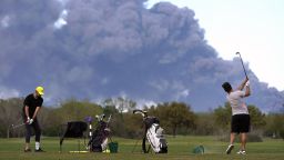Golfers practice at the Battleground Golf Course driving range as a chemical fire at Intercontinental Terminals Company continues to send dark smoke over Deer Park, Texas, Tuesday, March 19, 2019. (Melissa Phillip/Houston Chronicle via AP)