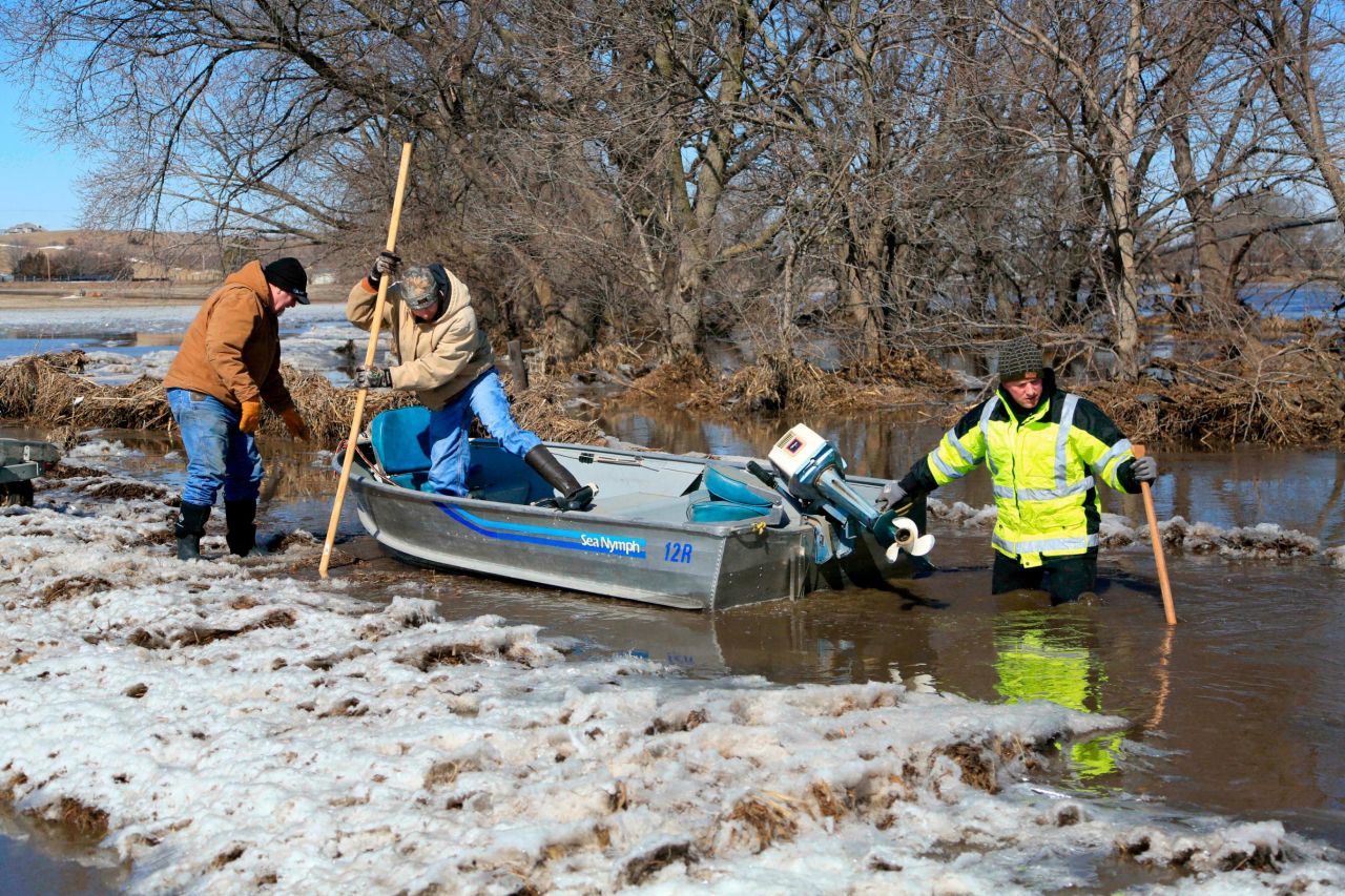 From left, Tom Wilke, his son Chad, and Nick Kenny launch a boat into the swollen waters of the North Fork of the Elkhorn River to check on Wilke's flooded property in Norfolk, Nebraska, on Friday, March 15.